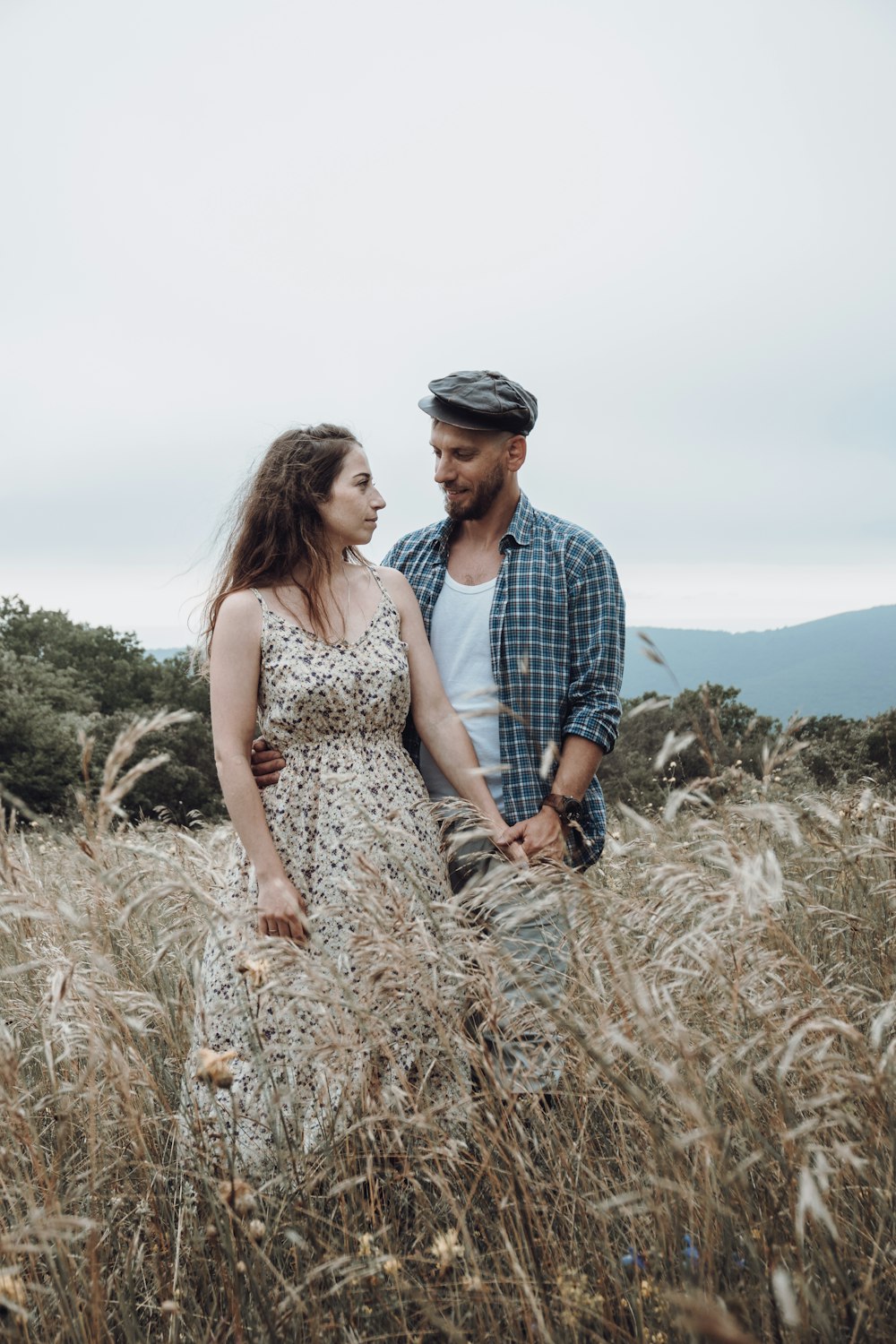 homme et femme debout sur le champ d’herbe brune pendant la journée
