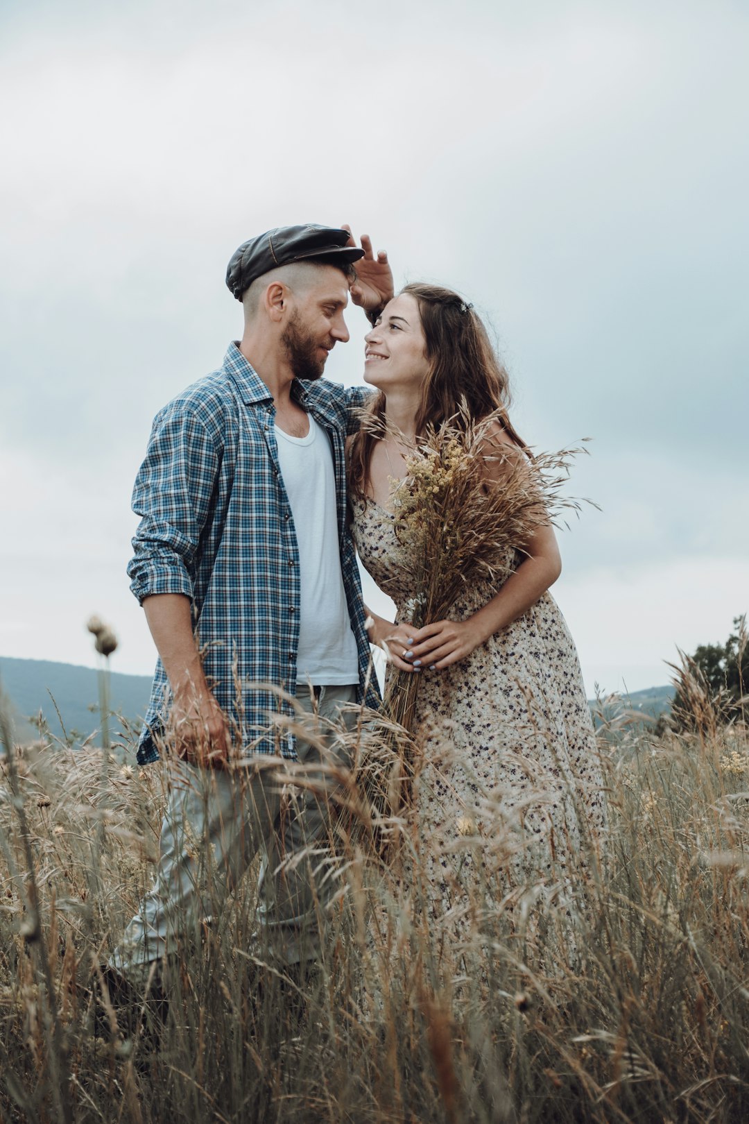 man and woman kissing on brown grass field during daytime