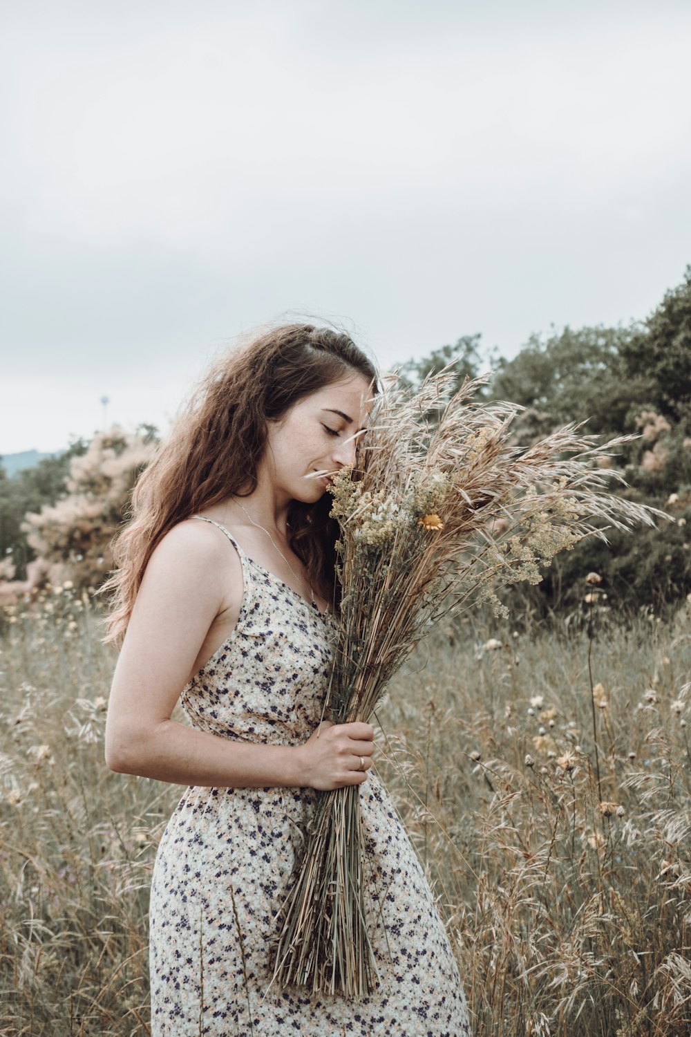 woman in white and black floral tank dress standing on green grass field during daytime