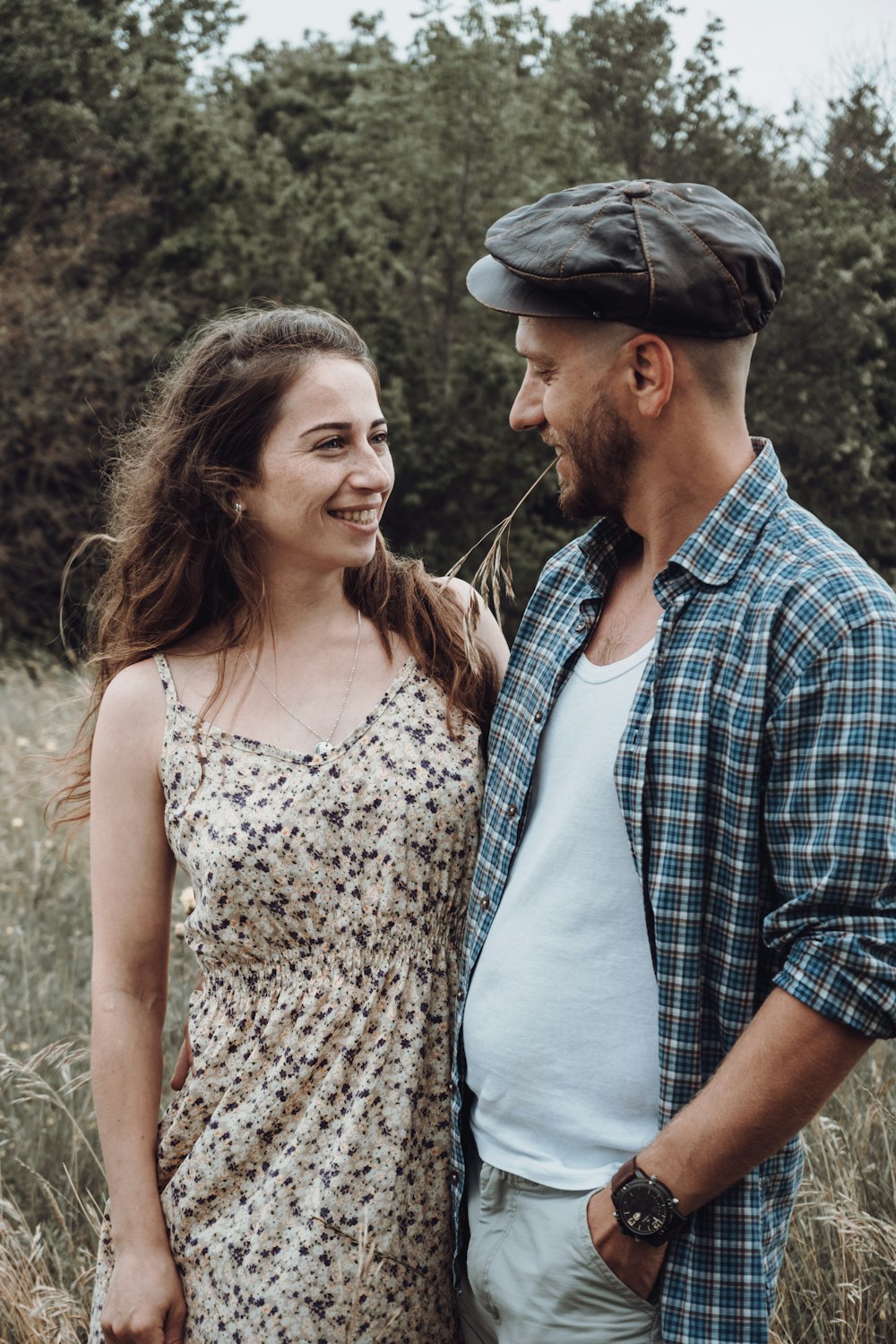 man in blue and white plaid dress shirt beside woman in white and black floral tank