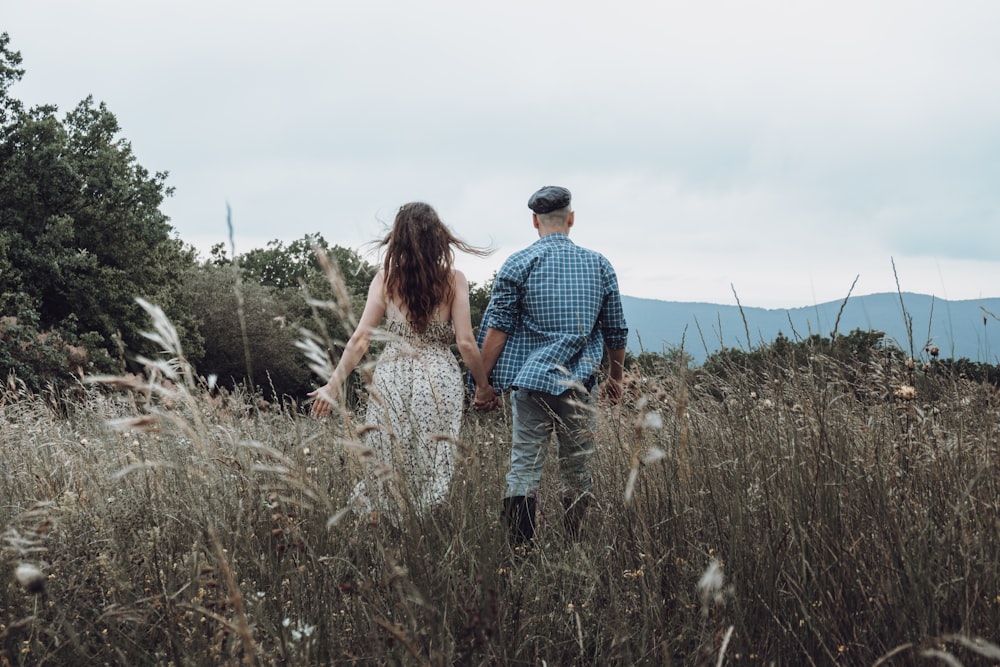 man and woman walking on grass field during daytime