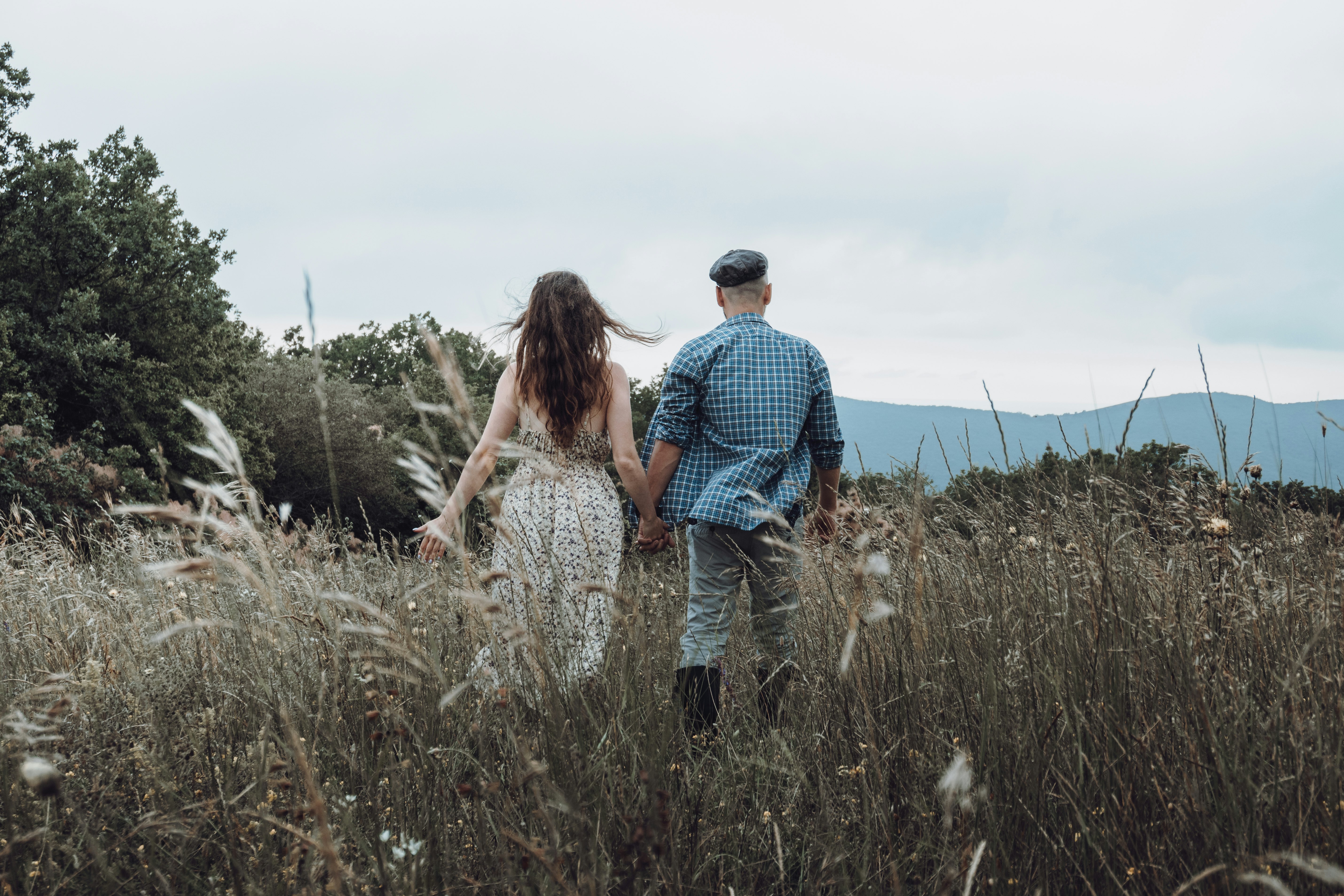 man and woman walking on grass field during daytime