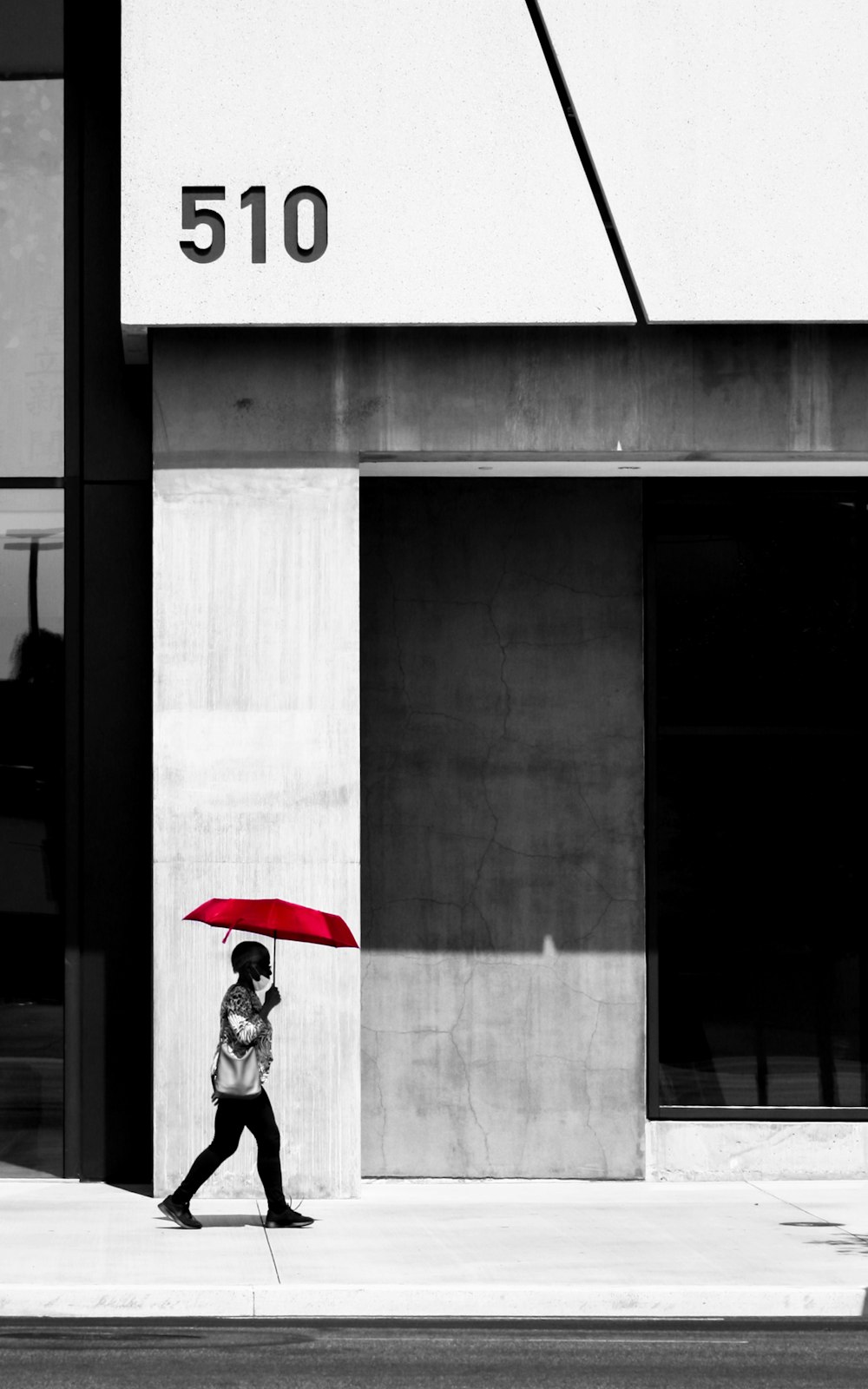 赤い傘を持つ黒いジャケットの女性