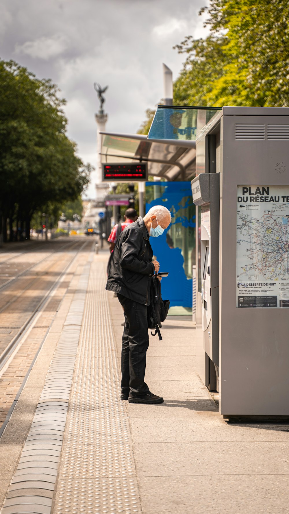 man in black jacket walking on sidewalk during daytime