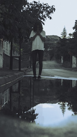 A quiet moment of reflection as a person sits alone near a small pool of water inside the sewer.