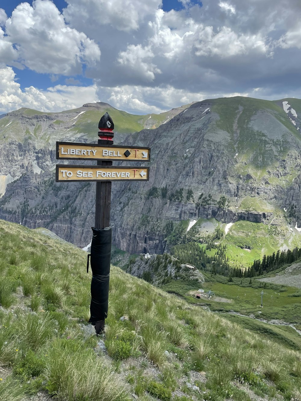 black and red street sign on green grass field near mountain during daytime