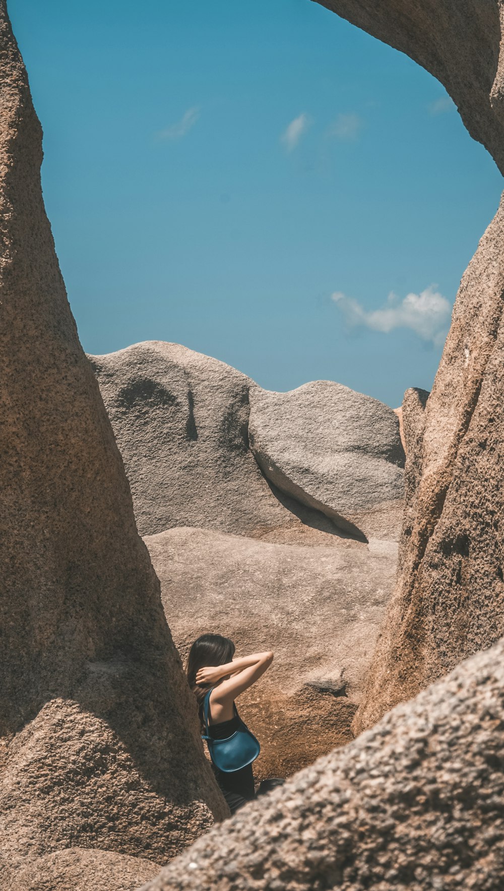 person in black tank top climbing on brown rock formation during daytime