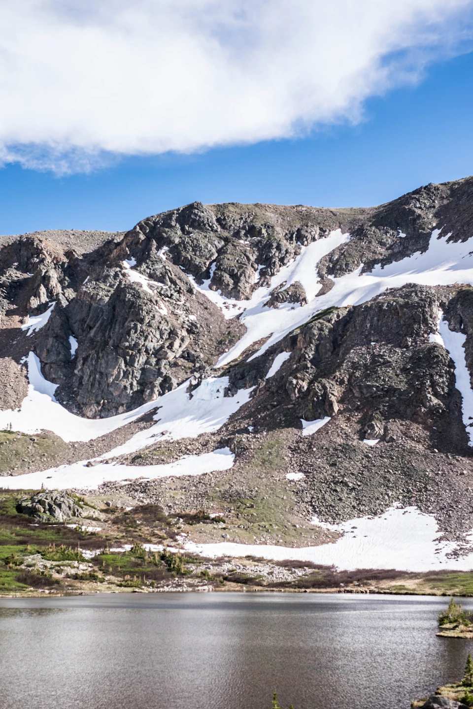 Serene mountain landscape with a large lake surrounded by snow-capped mountains and rocky cliffs