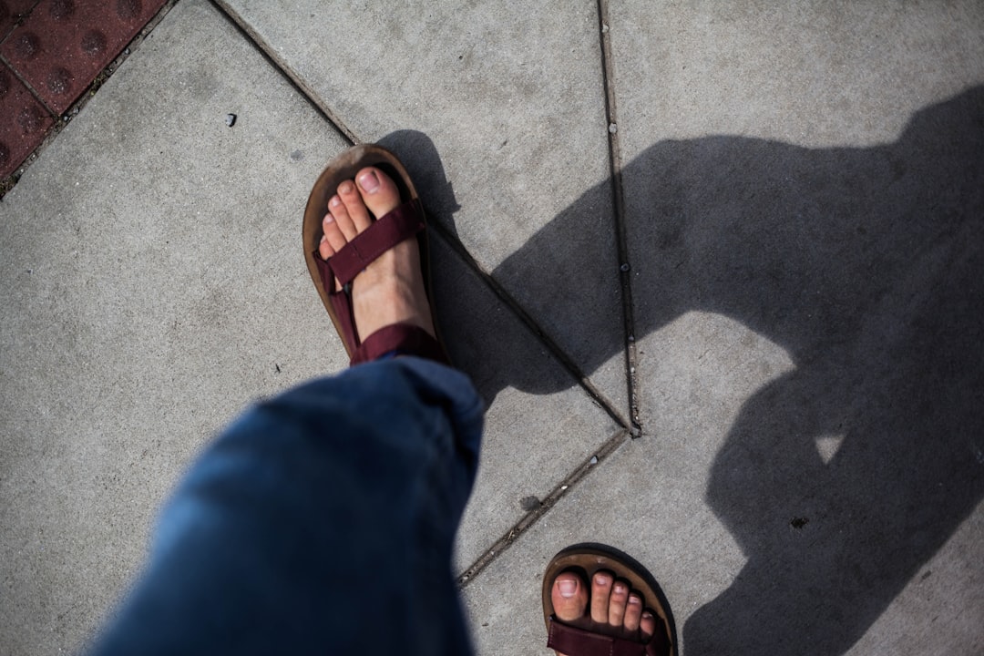 person in blue pants wearing brown leather sandals