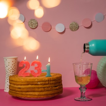 Pastel de cumpleaños con velas del número 23 y decoración festiva.