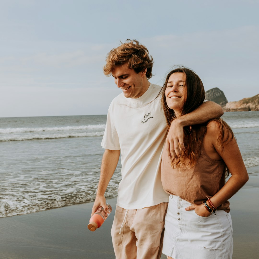 man in white crew neck t-shirt and woman in white t-shirt standing on beach