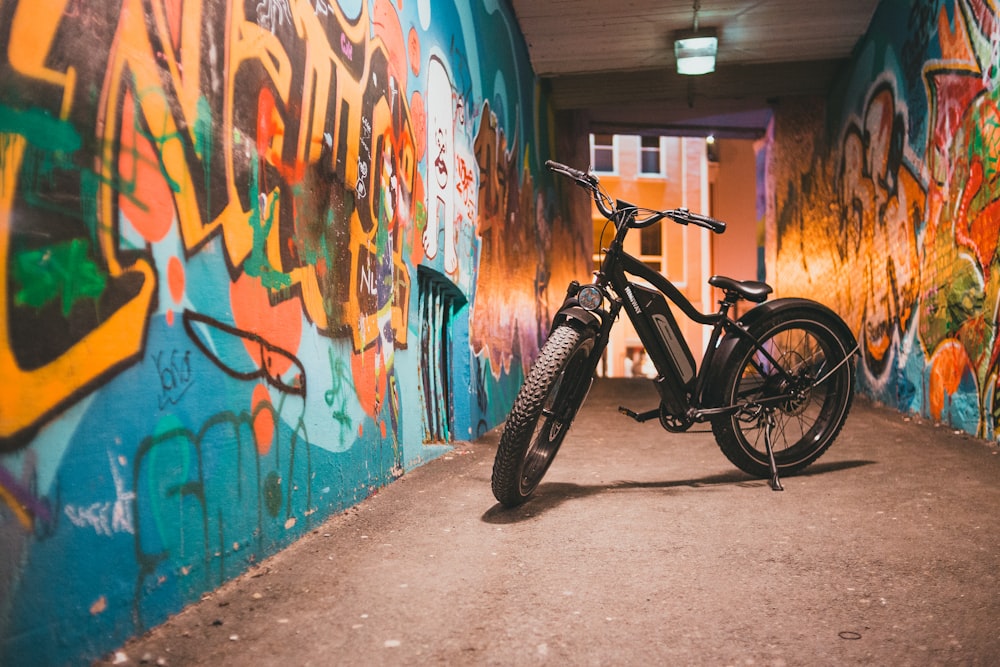 black bicycle parked beside wall with graffiti