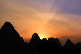 A panoramic view of the rugged karst hills rising dramatically from the water at sunset.