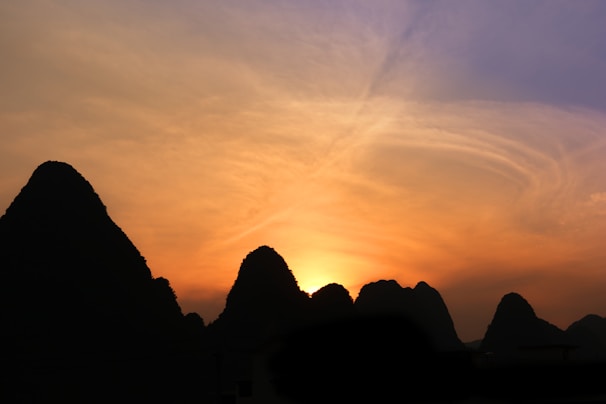 A panoramic view of the rugged karst hills rising dramatically from the water at sunset.