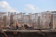 Workers assembling scaffolding on a commercial site with safety gear.