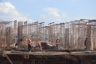 A diverse group of workers in safety gear collaborating on a construction site under a clear blue sky.