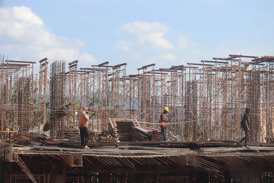 Construction workers assembling sturdy scaffolding on a building site during a sunny day.