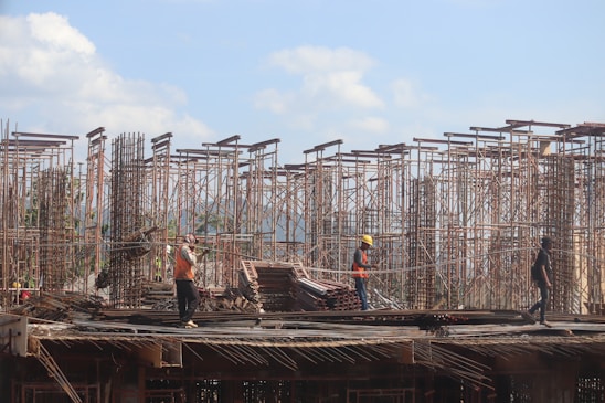 Construction workers collaborating on a modern building site with scaffolding and blueprints.