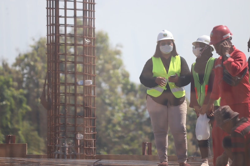 A group of diverse construction workers in safety gear smiling on a busy site.