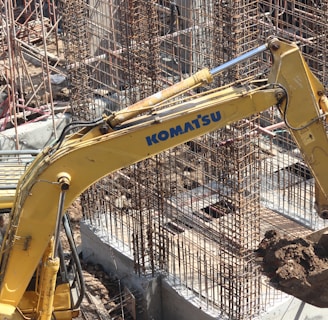 yellow excavator near gray metal fence during daytime