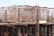 Scaffolding and construction materials form a complex structure, with metallic frameworks rising vertically. Several workers are present, engaging in construction tasks on an unfinished building.