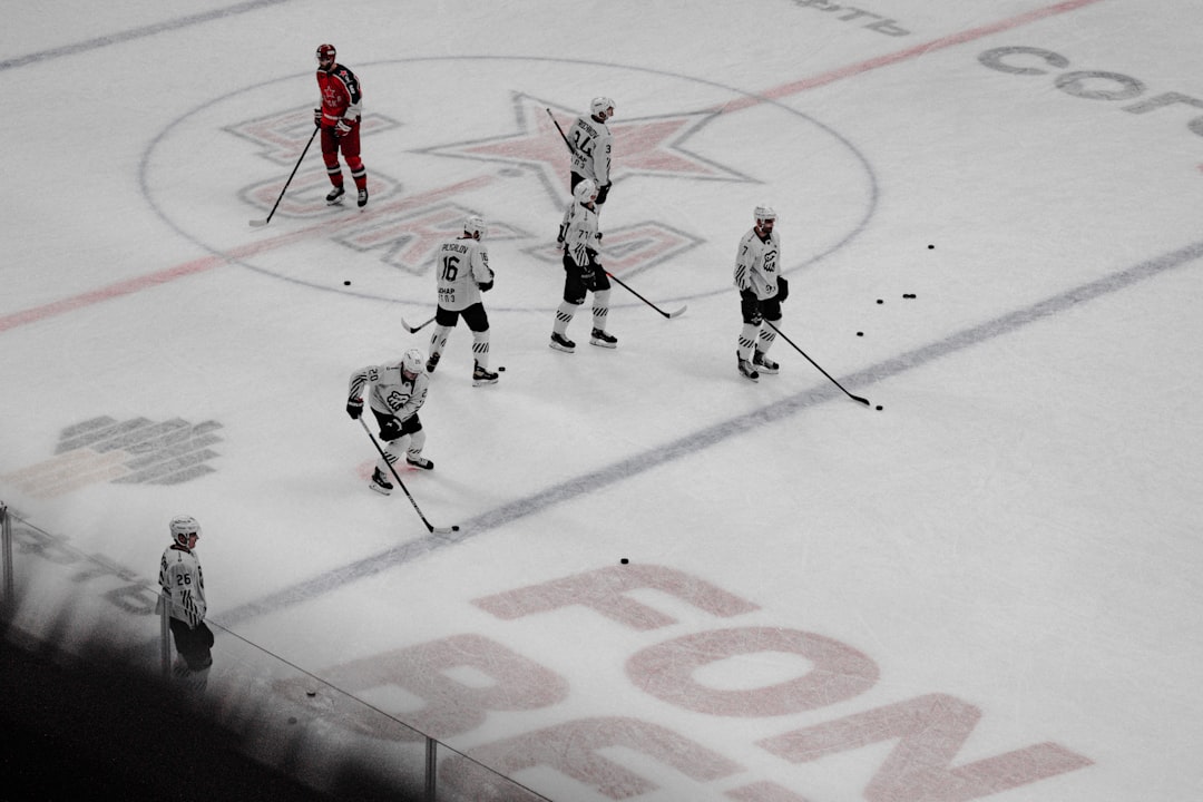 people playing ice hockey on ice field during daytime