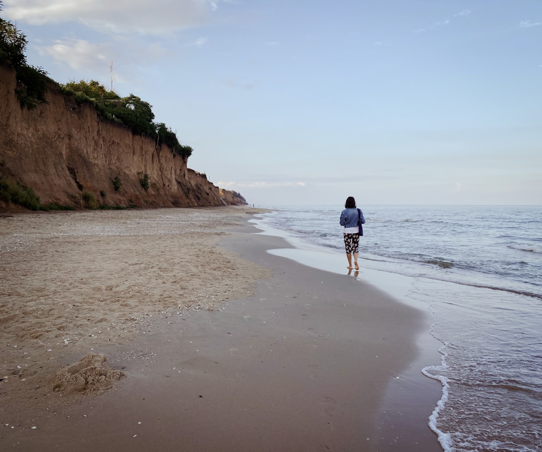 man in black shirt walking on beach during daytime