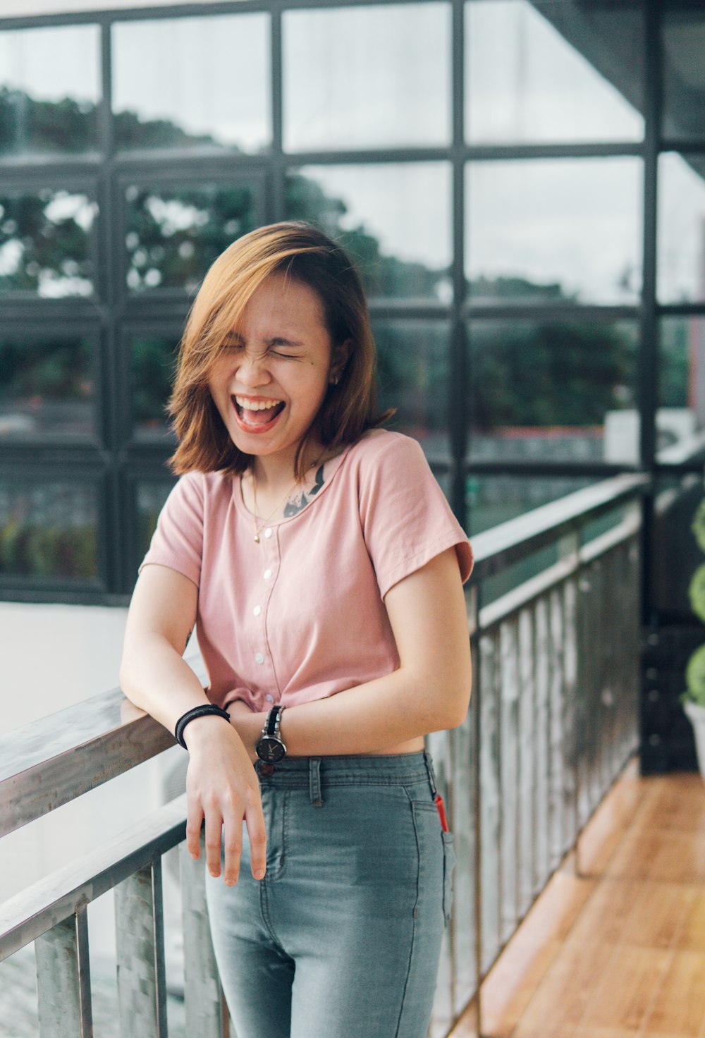 woman in pink shirt and blue denim shorts sitting on brown wooden bench during daytime