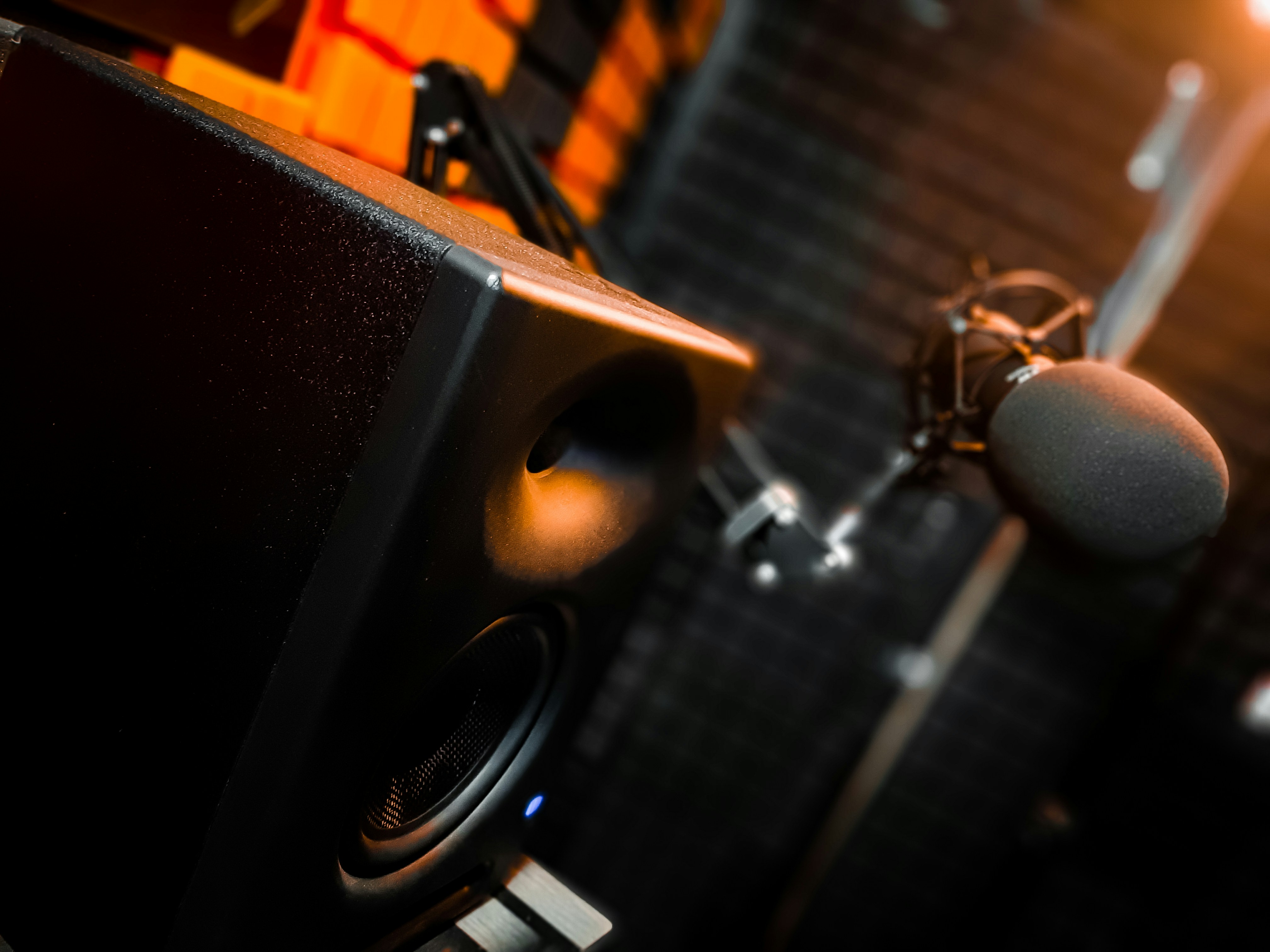 Male musician in recording booth, moody amber lighting, dark wood panels, recording microphone in foreground