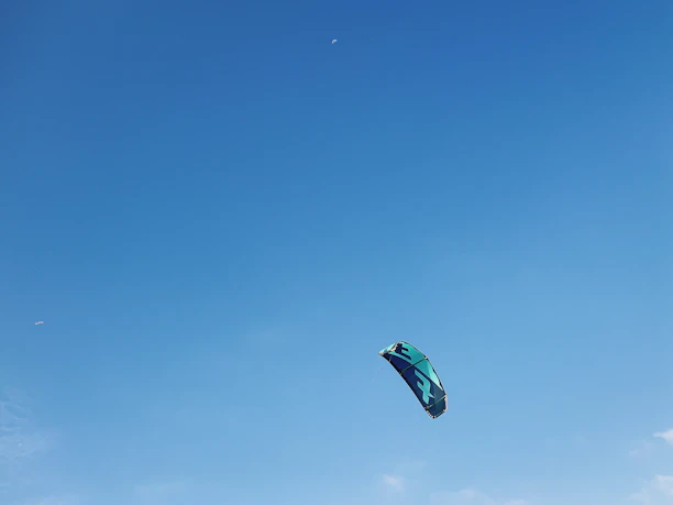 A vibrant red and yellow fighter kite soaring against a clear blue sky.