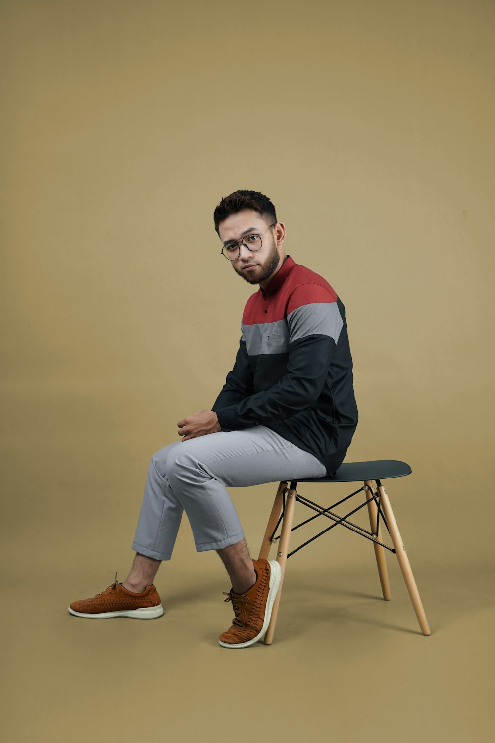 man in black and red long sleeve shirt and gray pants sitting on brown wooden folding