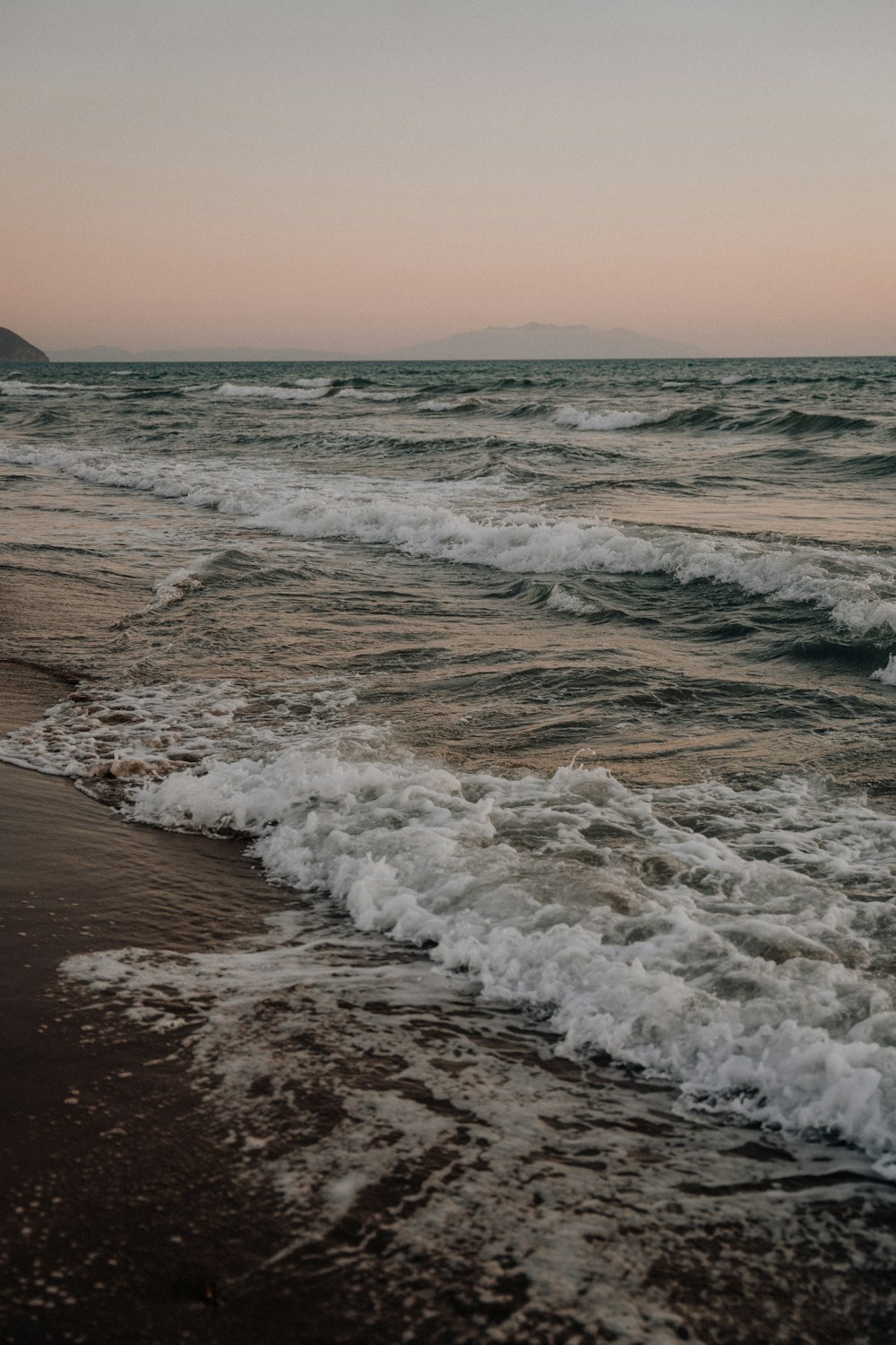 ocean waves crashing on shore during sunset