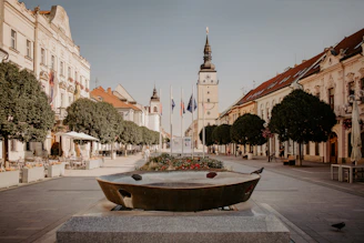 A serene European town square bathed in golden afternoon light, with cobblestone streets and colorful buildings.