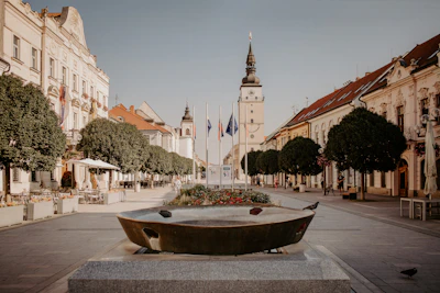 A serene European town square bathed in golden afternoon light, with cobblestone streets and colorful buildings.