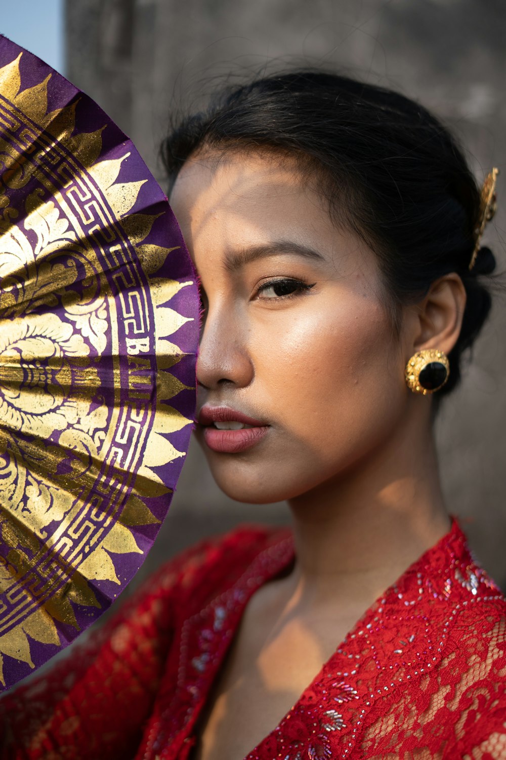 a woman in a red dress holding a purple and gold umbrella