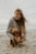 woman in gray knit sweater hugging brown short coated dog on beach during daytime