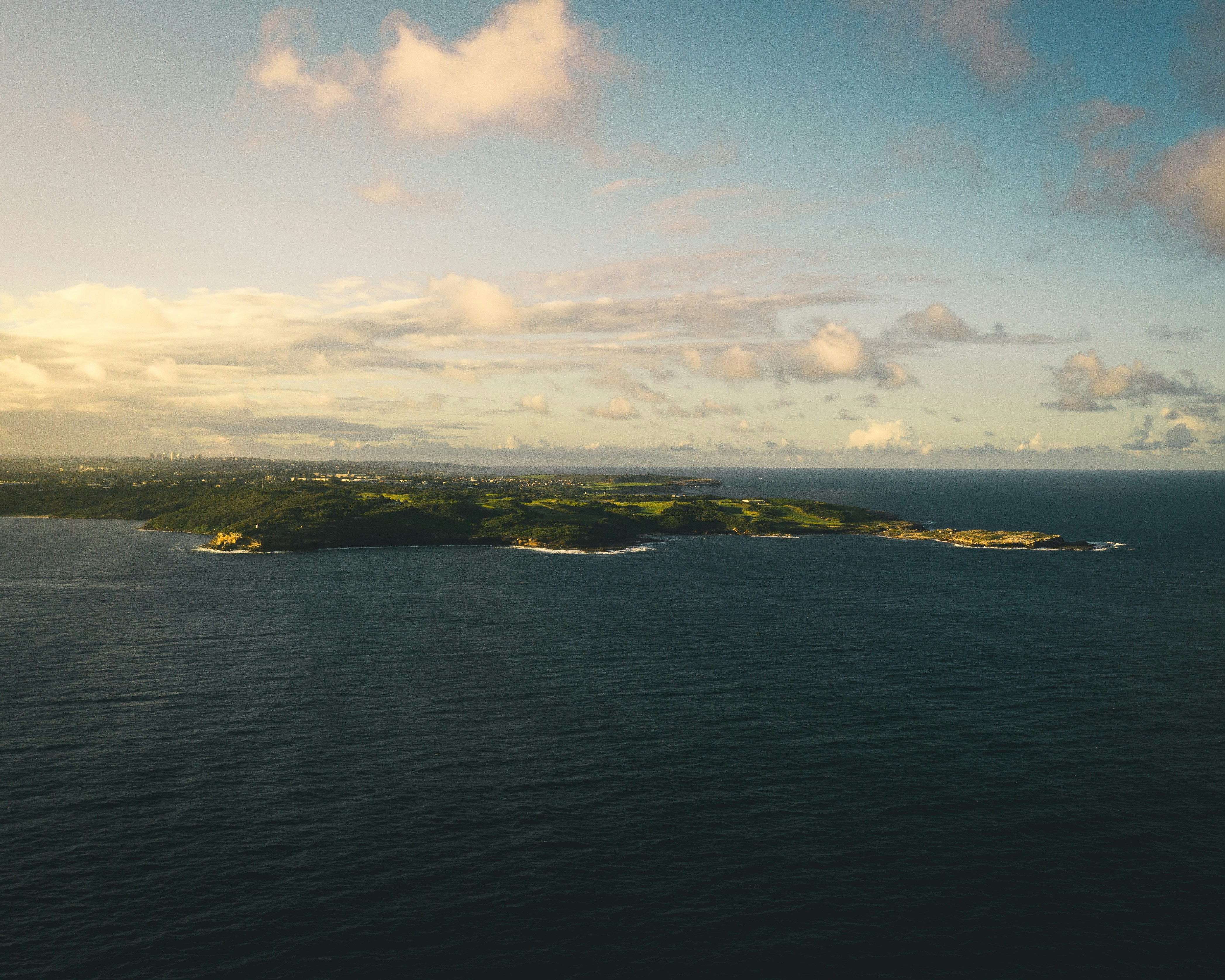 green island under blue sky and white clouds during daytime