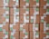 A stack of cardboard boxes with various labels and stickers, arranged in a neat and organized manner. Each box has handwritten numbers and multiple shipping labels, some of which are on tape that seals the boxes.