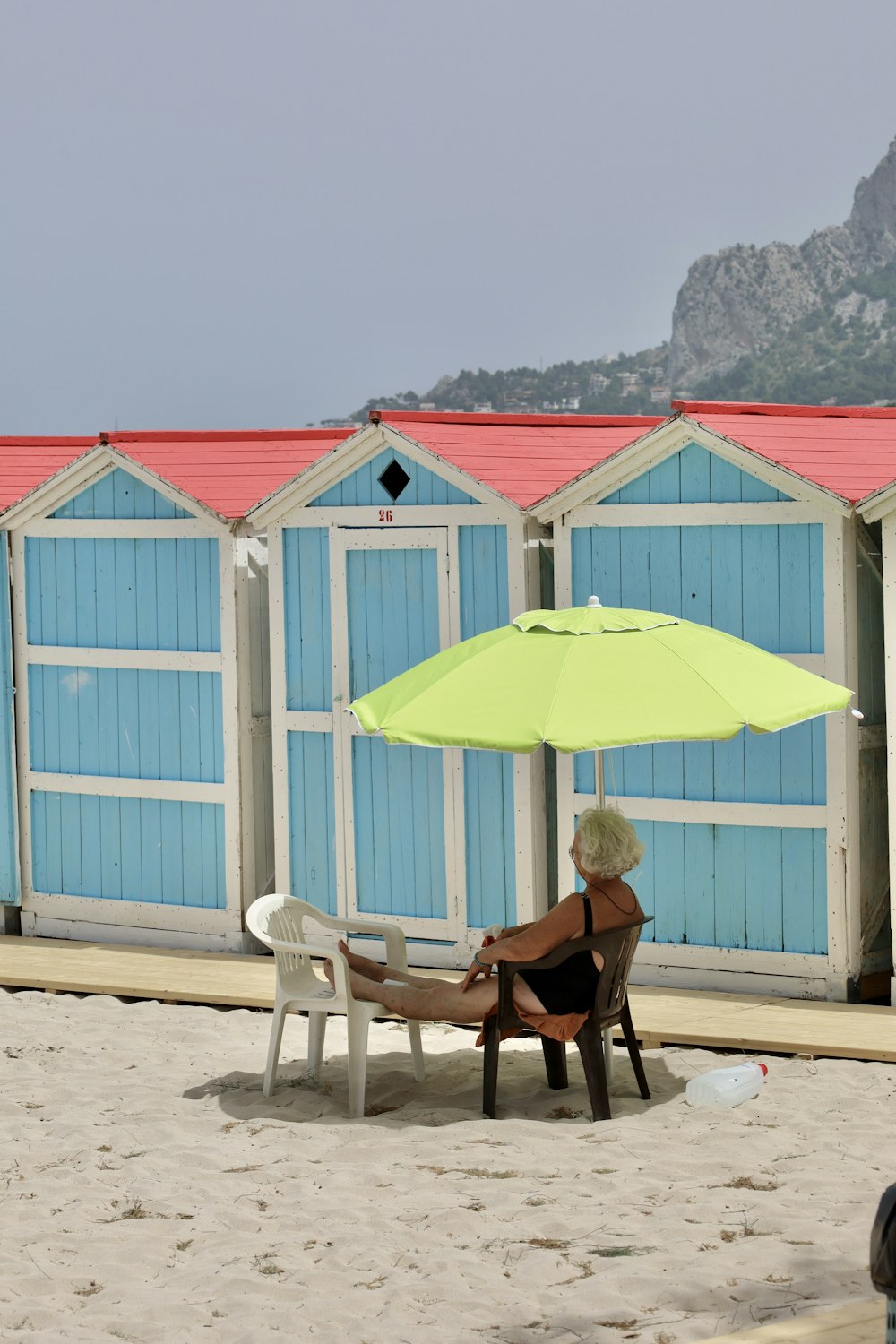 woman sitting on chair under yellow umbrella during daytime