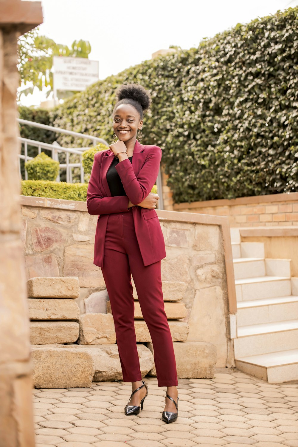 woman in red blazer and brown pants standing on brown concrete stairs