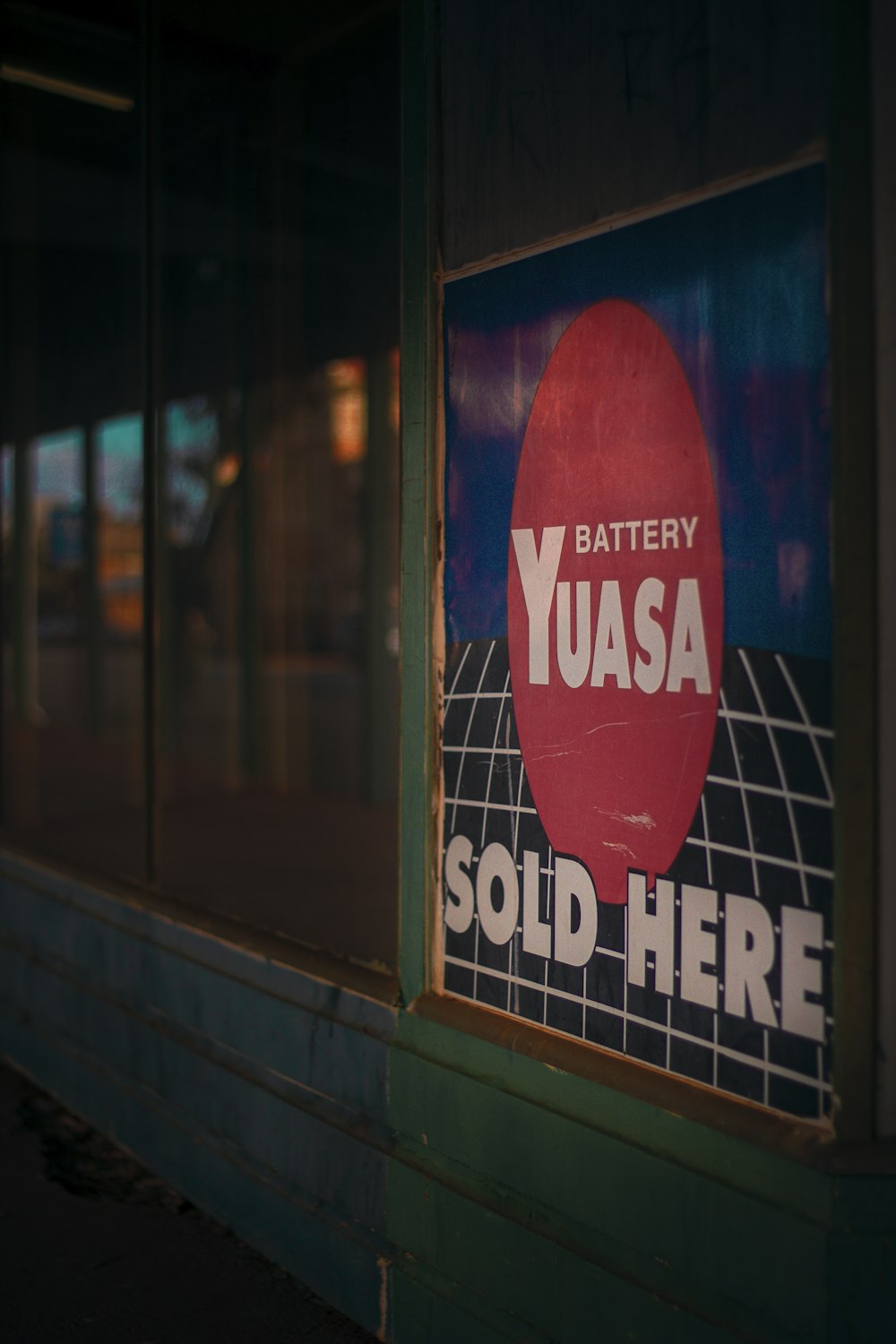a sign on the side of a building that says battery yuasa sold here