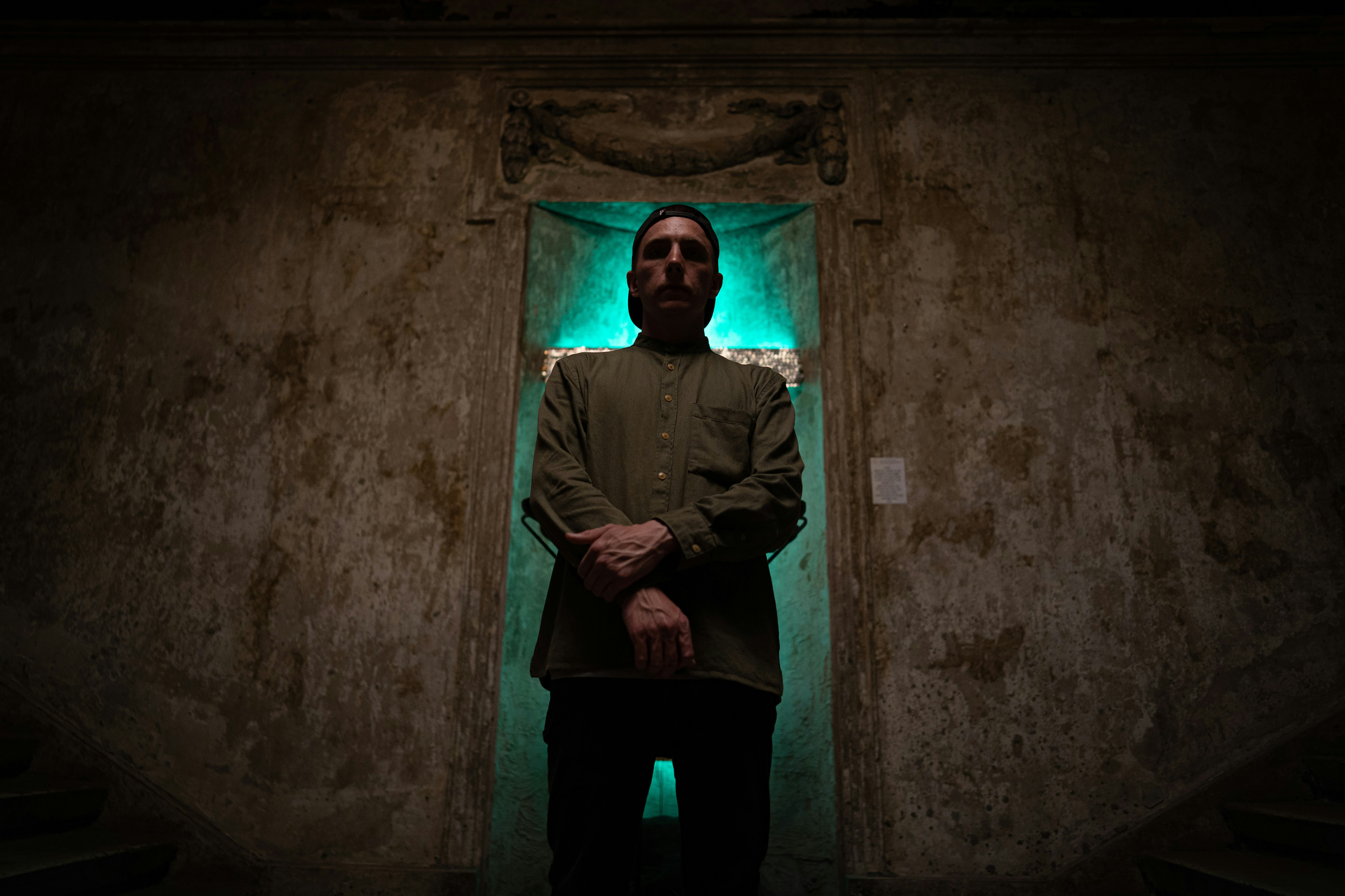 Hombre con chaqueta negra y pantalones negros de pie sobre el suelo de hormigón gris