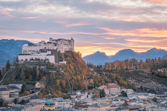 white and brown concrete building near green trees during daytime in Salzburg Austria