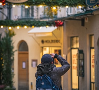 man in black jacket taking photo of store during daytime