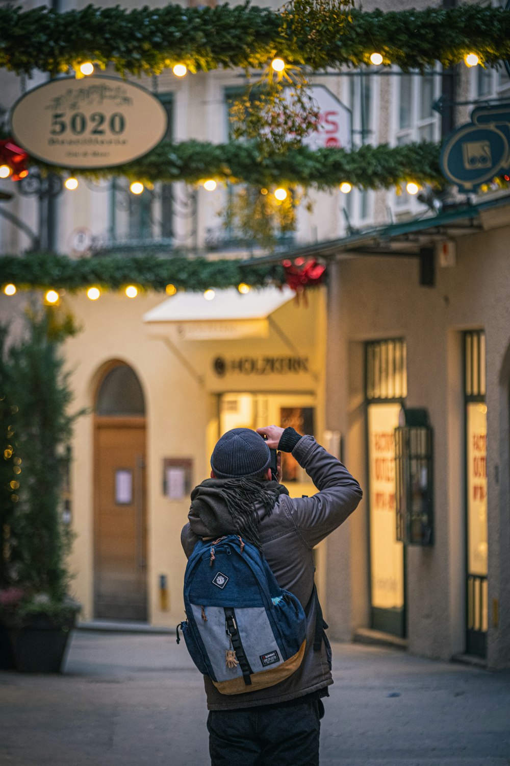 man in black jacket taking photo of store during daytime