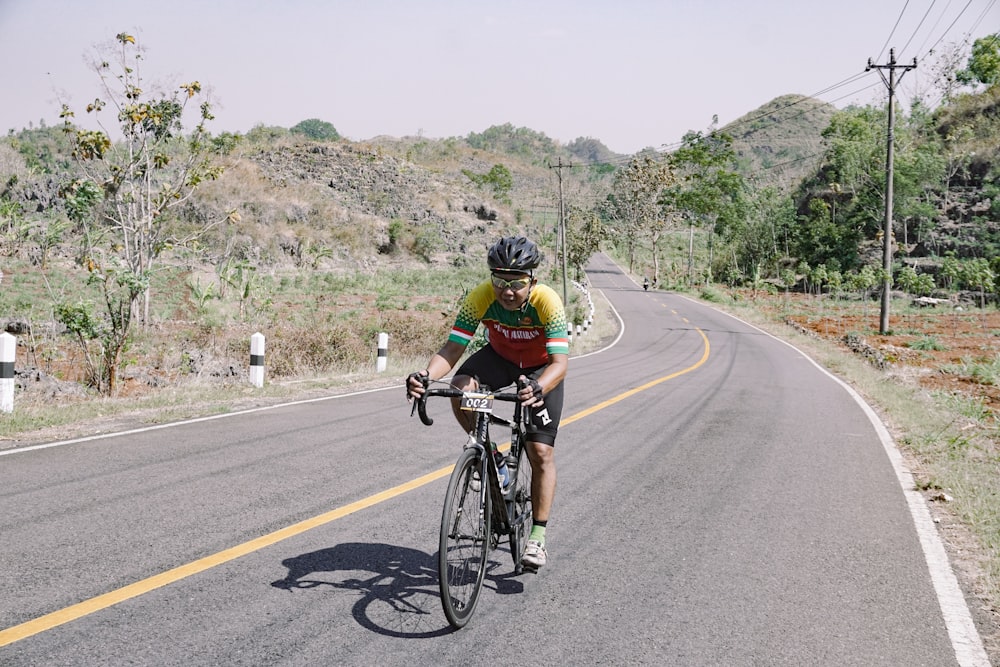 man in black and yellow shirt riding bicycle on road during daytime