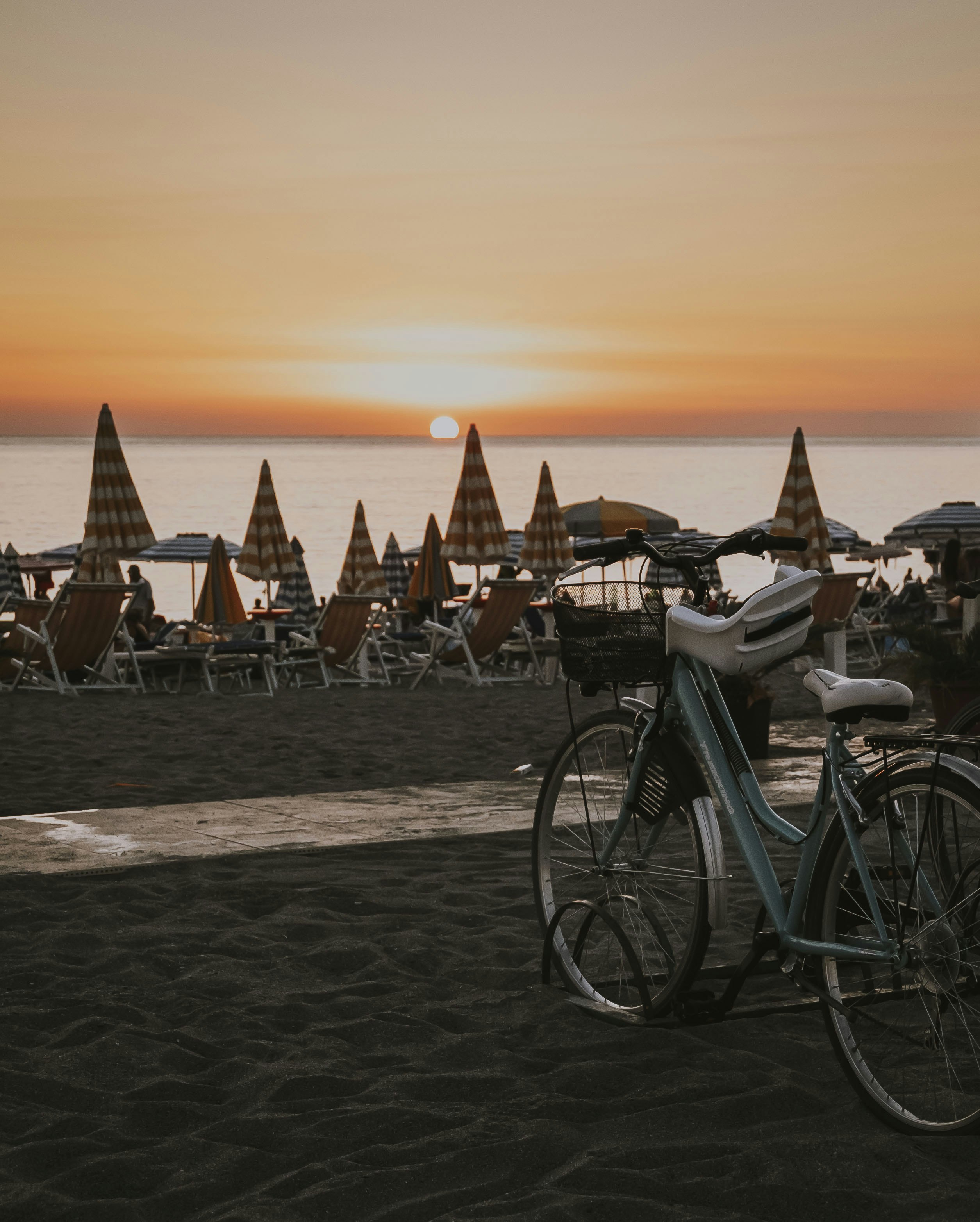 black city bike on beach during sunset