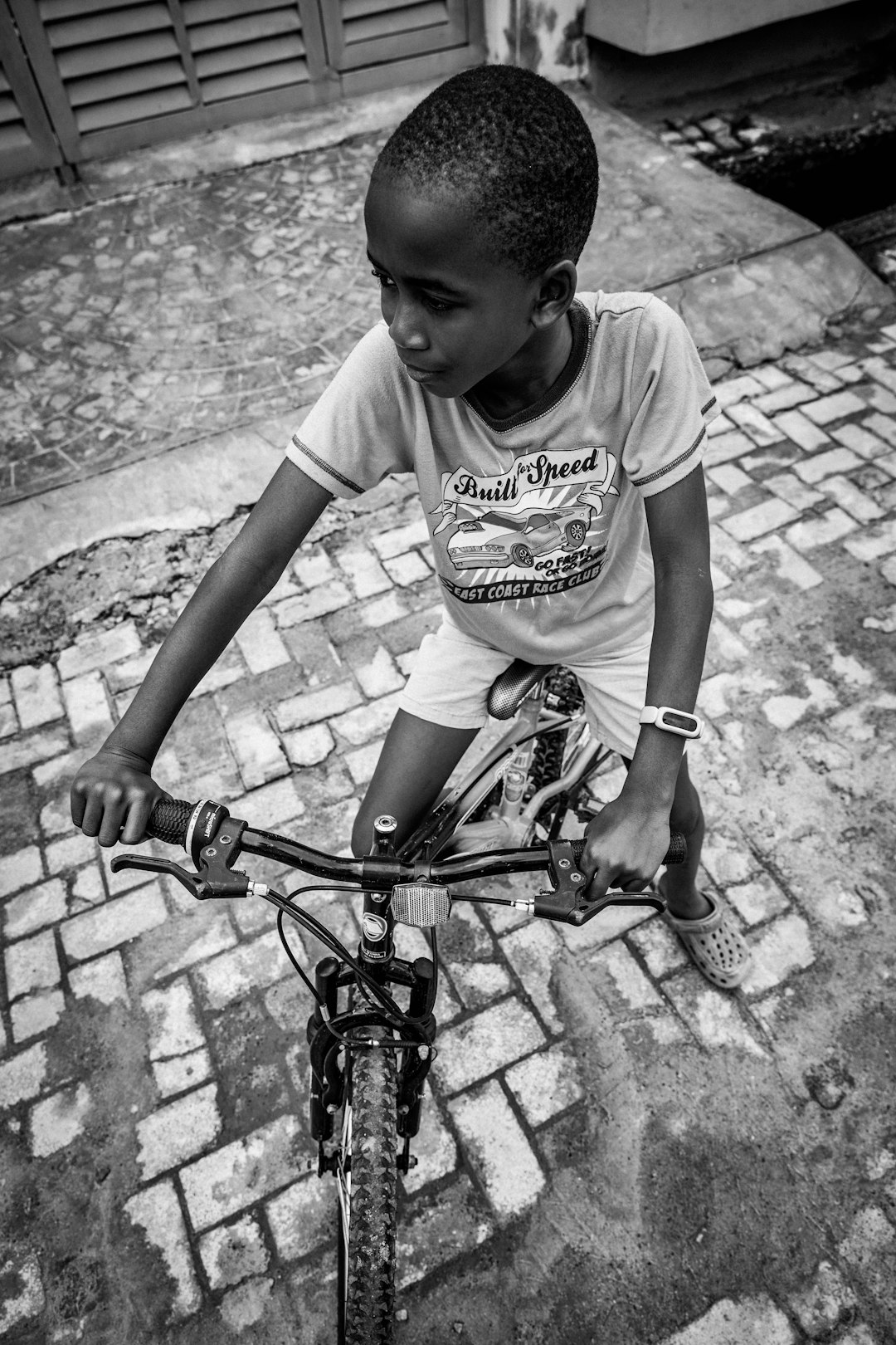 grayscale photo of boy in white crew neck t-shirt riding bicycle