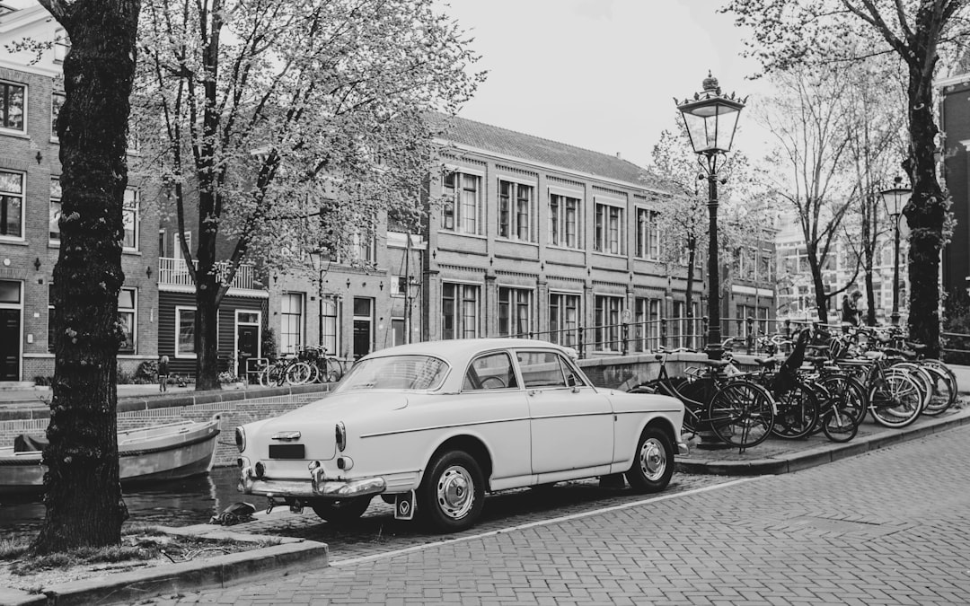 grayscale photo of classic car parked near building