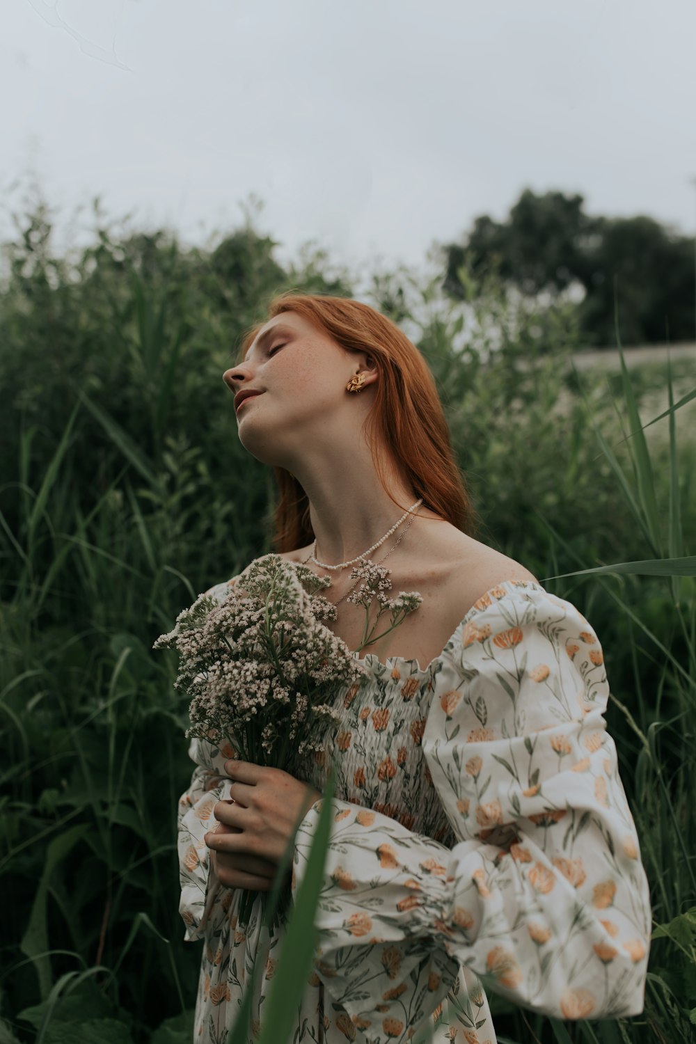 woman in white and brown floral off shoulder dress standing on green grass field during daytime